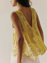 Load image into Gallery viewer, A woman shown from the back wearing a sheer yellow sleeveless top with metallic geometric embroidery and a deep V-neckline, paired with white pants against a plain light background.