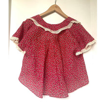 Load image into Gallery viewer, Red floral blouse with white lace trim on a hanger against a white background