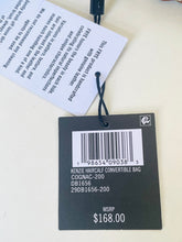 Load image into Gallery viewer, A black product tag and white informational hangtag attached with a black string, photographed on a light beige surface. The black tag shows a barcode and text including 'KENZIE HAIRCALF CONVERTIBLE BAG', 'COGNAC-200', and 'MSRP $168.