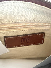 Load image into Gallery viewer, Close-up of the interior of a FRYE bag, showing a cream canvas lining, a brown leather brand patch with white stitching, and a zipper.