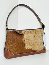 Load image into Gallery viewer, A shoulder handbag featuring a brown and beige cowhide patterned body with smooth brown leather trim, a top zipper, and a single shoulder strap, shown against a plain white background.