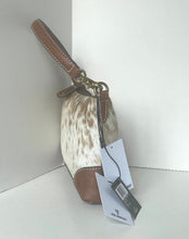 Load image into Gallery viewer, A small handbag with a cowhide body, brown leather trim, and a brown shoulder strap, shown with retail tags hanging from the handle against a plain light gray background.