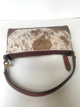Load image into Gallery viewer, A small handbag with a brown and white cowhide patterned front, brown leather trim, a brown zipper, and a brown shoulder strap, shown on a plain white background.