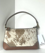 Load image into Gallery viewer, A handbag with a brown and white cowhide patterned body, solid brown leather trim, and a brown shoulder strap, shown with a white hangtag on a white background.