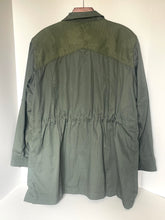 Load image into Gallery viewer, An olive green utility jacket with a textured patterned yoke and a gathered waist, shown hanging against a plain white background.