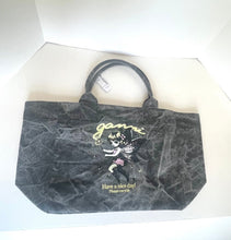 Load image into Gallery viewer, A black canvas tote bag with a marbled texture, featuring a cartoon character graphic and gold text on the front, displayed inside a white box.