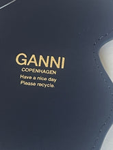 Load image into Gallery viewer, Close-up of a dark navy blue GANNI bag with gold lettering that reads 'GANNI COPENHAGEN Have a nice day Please recycle.'