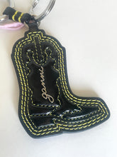 Load image into Gallery viewer, A black faux-leather cowboy boot keychain with yellow contrast stitching, featuring a silver metal key ring and a black and yellow strap.