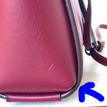 Load image into Gallery viewer, Close-up of a maroon handbag with visible wear on a white background