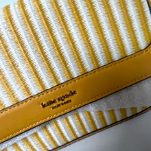 Load image into Gallery viewer, Close-up of a yellow and white striped pouch with 'kate spade' branding.