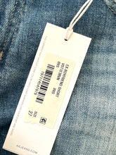 Load image into Gallery viewer, Close-up of a jeans tag with product details on a denim background