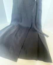 Load image into Gallery viewer, A dark gray apron laid flat on a light-colored surface, showing its front bib, waist ties, and wide apron body.