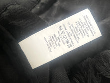 Load image into Gallery viewer, Clothing label on a black fabric background