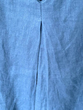 Load image into Gallery viewer, A close-up of a blue textured fabric, likely linen or a linen-blend shirt, showing a central vertical seam and a subtle woven texture.