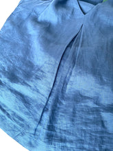 Load image into Gallery viewer, A close-up of a blue linen or cotton garment fabric, showing the textured weave and a V-neckline detail against a white background.