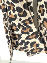 Load image into Gallery viewer, Close-up of a leopard print garment, showing a beige base with black and brown spots, with a side pocket detail.