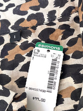 Load image into Gallery viewer, Close-up of a leopard-print garment with a Simons retail price tag attached. The fabric pattern shows beige, brown, black, and off-white tones, and the Simons tag is clearly visible with the brand name and price $99.