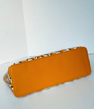Load image into Gallery viewer, An orange faux-leather cosmetic pouch with a patterned fabric trim, photographed on a white background.