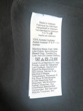 Load image into Gallery viewer, Fabrication label on a dark fabric background