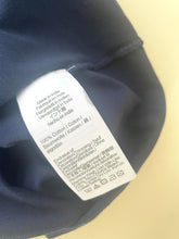 Load image into Gallery viewer, Clothing label on a dark fabric background