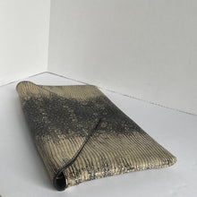 Load image into Gallery viewer, A metallic gold and black snakeskin-patterned clutch bag resting on a white surface.