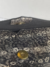 Load image into Gallery viewer, Close-up detail of a textured black and silver snakeskin-patterned bag with a gold-tone snap button and a silver-toned decorative clasp.