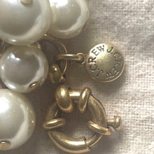 Load image into Gallery viewer, Gold and pearl earring with &#39;J.Crew&#39; label on a textured fabric background