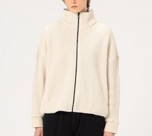 Load image into Gallery viewer, Person wearing a cream ribbed knit sweater with a zipper on a white background