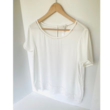 Load image into Gallery viewer, White blouse with lace details on a wooden hanger against a white background