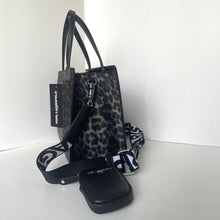 Load image into Gallery viewer, Black handbag with leopard print pattern and visible brand tag on a white background