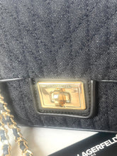 Load image into Gallery viewer, Close-up of a black quilted denim handbag with a gold-tone metal clasp featuring the 'SARAGO CEFALD' brand name, with a gold chain strap partially visible on the left.