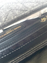 Load image into Gallery viewer, Close-up of a black Karl Lagerfeld wallet or clutch showing the brand name on a black zipper tab, textured black exterior, white stitching, and a small gold logo accent.