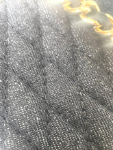 Load image into Gallery viewer, Close-up of a black quilted fabric texture with a gold chain detail visible in the top right corner.