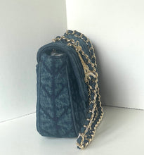 Load image into Gallery viewer, A dark blue denim shoulder bag with a quilted chevron pattern and a gold-tone chain strap, leaning against a white corner wall.