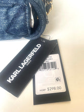 Load image into Gallery viewer, A close-up of a blue denim handbag with attached Karl Lagerfeld Paris tags, including a black brand hangtag and a white price label, on a light beige background.