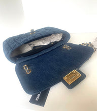 Load image into Gallery viewer, A navy blue quilted fabric handbag with gold-tone hardware, shown open with its interior lining visible. A Karl Lagerfeld brand tag is attached near the bottom, and part of a chain strap is visible on the right.