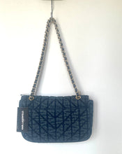 Load image into Gallery viewer, A dark navy quilted leather shoulder bag with a chain strap, hanging against a plain white wall. A black paper tag on the side reads 'DAKLA LADY &amp; FIELD'.