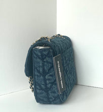 Load image into Gallery viewer, A dark blue quilted monogram handbag with a silver chain strap, standing upright in a white corner.