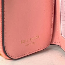 Load image into Gallery viewer, Close-up of a pink wallet with 'kate spade New York' branding.