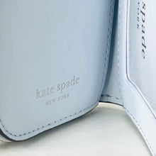 Load image into Gallery viewer, Light blue wallet with 'kate spade New York' branding on a light gray background