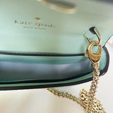 Load image into Gallery viewer, Gold chain strap of a Kate Spade handbag on a light green background