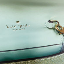 Load image into Gallery viewer, Close-up of a light blue handbag with 'kate spade New York' branding.