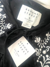 Load image into Gallery viewer, Black garment with white floral embroidery and 'kate spade' label.