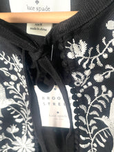 Load image into Gallery viewer, Black fabric with white floral embroidery and 'kate spade' label.