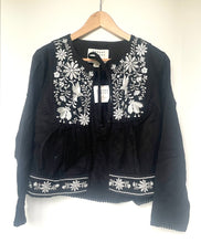 Load image into Gallery viewer, Black blouse with white floral embroidery on a hanger against a white background