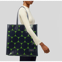 Load image into Gallery viewer, Person holding a black tote bag with green circle pattern on a plain background