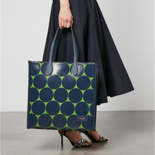 Load image into Gallery viewer, Person holding a blue and green patterned tote bag with a plain background