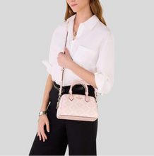 Load image into Gallery viewer, Woman holding a pink handbag against a light gray background