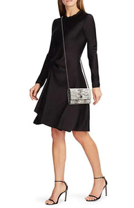 Woman is wearing a small Kurt Geiger shoulder bag and a black cocktail dress.