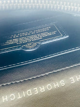 Load image into Gallery viewer, Close-up of a leather-bound book with embossed text and a visible brand name.